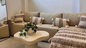 Un salon moderne avec un canapé beige, une table basse ronde et un grand tableau accroché au mur.
