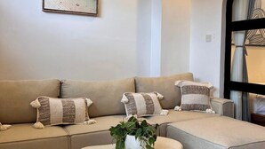 Un salon moderne avec un canapé d’angle, une table basse et un tableau accroché au mur.