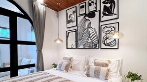 Une chambre avec un grand lit, un plafond en bois et des œuvres d’art accrochées au mur.