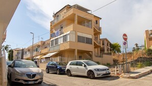 A multi-story residential building with balconies, parked cars, and a no parking sign. - Beautiful apartment in Marina di Ragusa with house sea view (Marina di Ragusa)