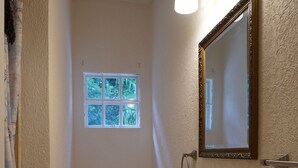 A compact bathroom with a toilet, sink, and a mirror with lights. - Designer Loft on Queen W | 10ft ceilings, parking (Toronto)