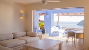 Una sala de estar moderna con un sofá, una mesa de centro y vista al océano a través de un amplio ventanal.