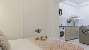 Une chambre à coucher avec un lit, une table de chevet ornée d’une plante et un plateau avec une tasse et une soucoupe.