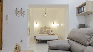 Une chambre moderne avec un lit, des lampes de chevet, un luminaire suspendu et une étagère intégrée pour un four à micro-ondes.