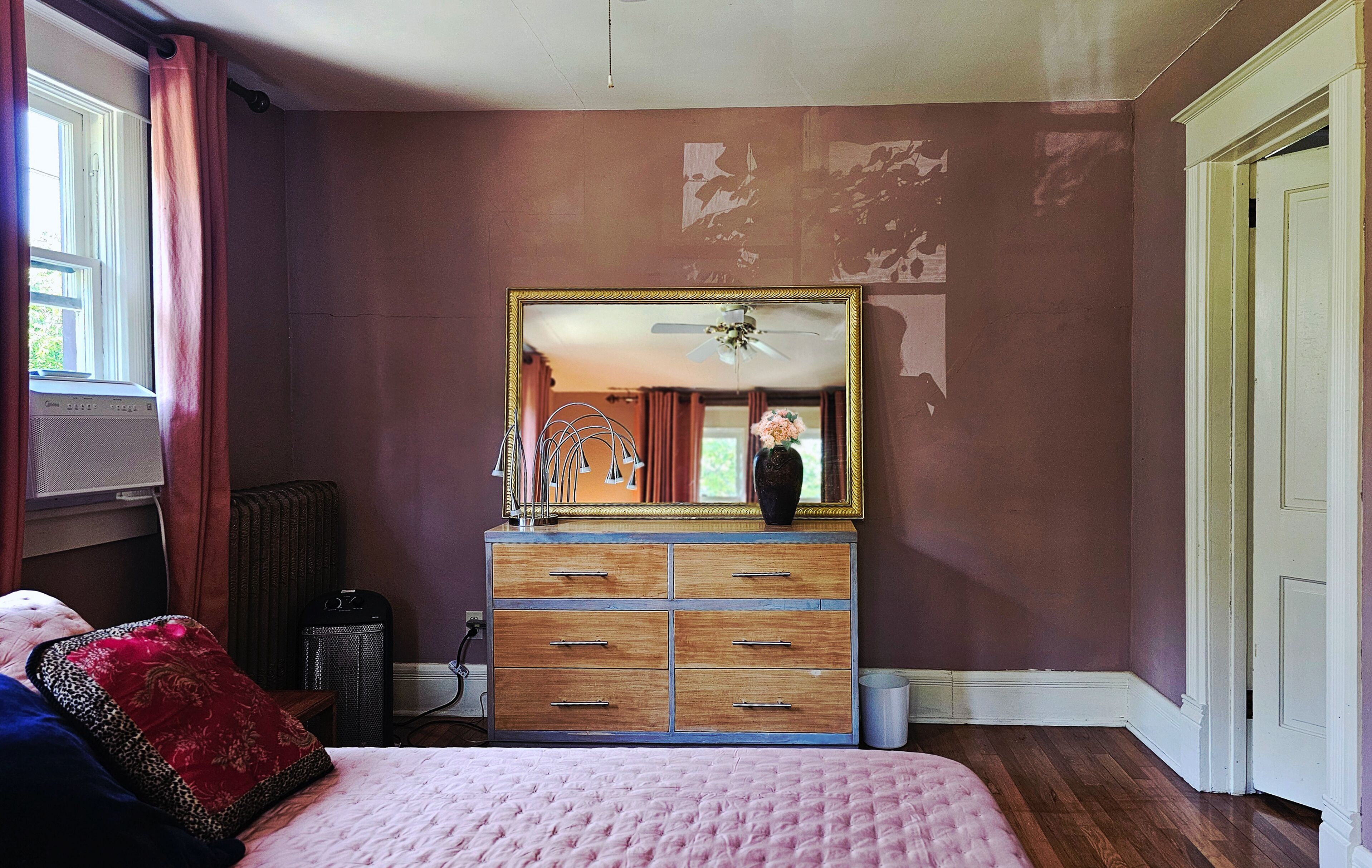 Une chambre à coucher avec un lit, une commode, un miroir et un radiateur.