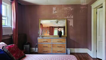 Une chambre à coucher avec un lit, une commode, un miroir et un radiateur.