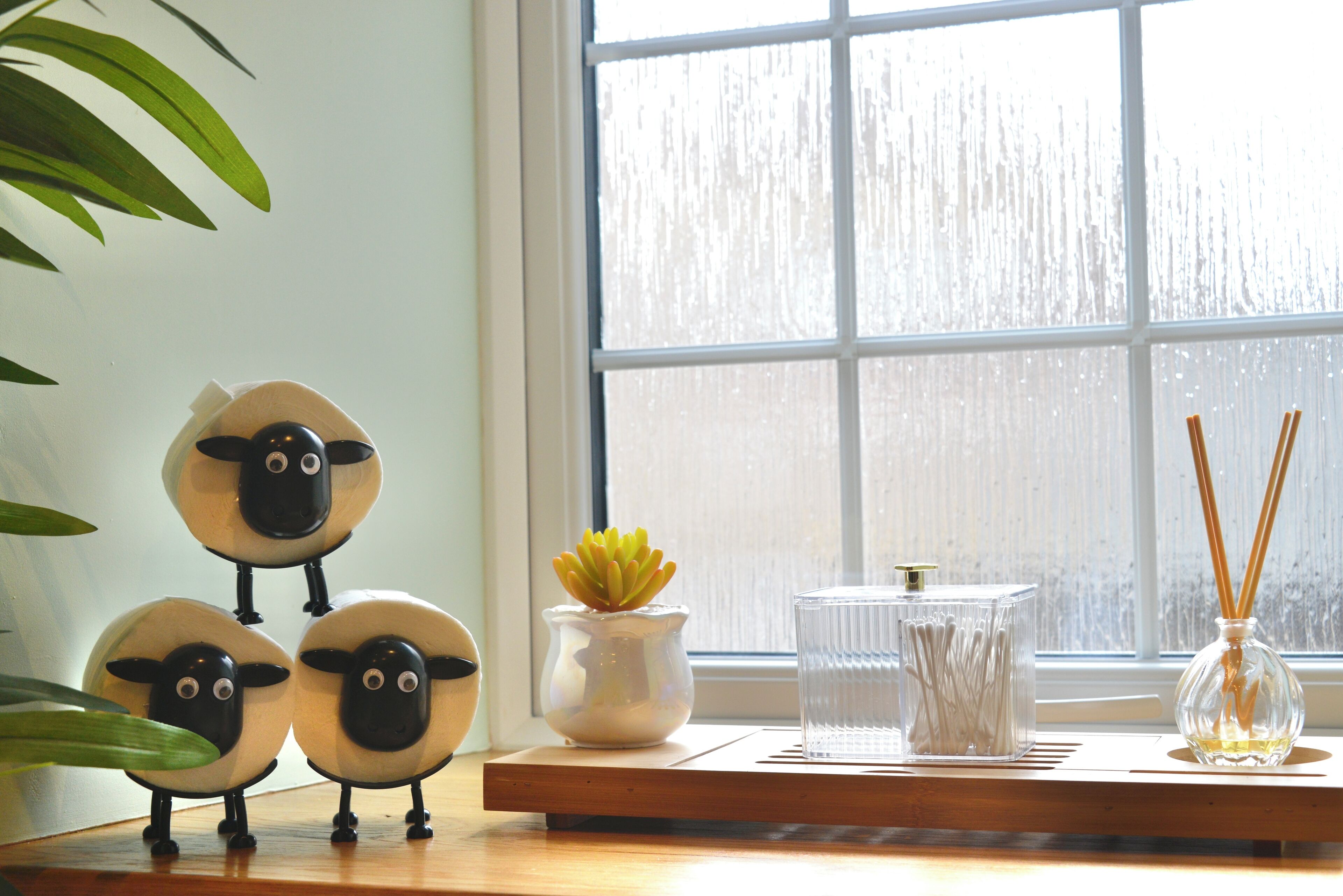 A window with a view of a snowy landscape, a wooden shelf with decorative items, and a potted plant.
