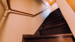 Una escalera de madera con barandilla y una lámpara colgante.