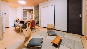 Una habitación moderna con esteras de tatami, un escritorio de madera y una puerta oscura.