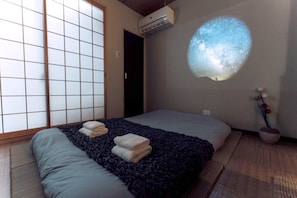 A room with a bed, a futon, a sliding shoji screen, a projector, and a small plant. - mist Osaka - Private Outdoor Sauna & Projector (Osaka)