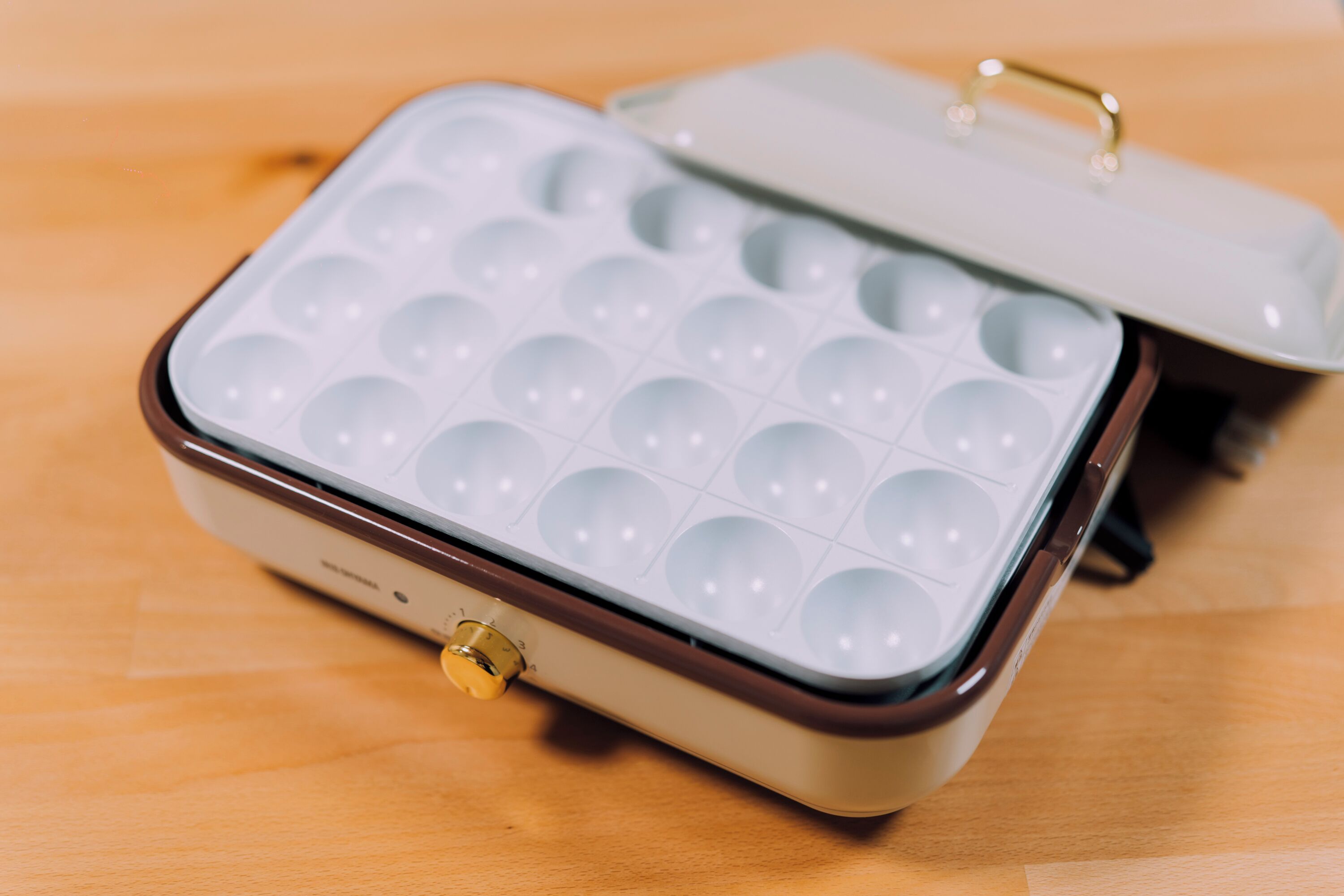 A portable ice cube tray with a handle, placed on a wooden surface.