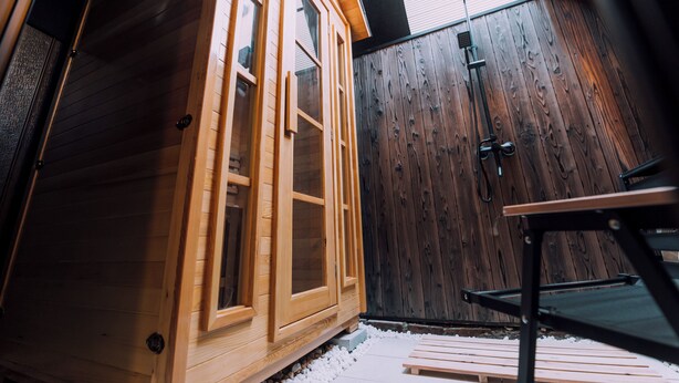 Una cabaña de madera con ventanas grandes y una puerta también de madera.