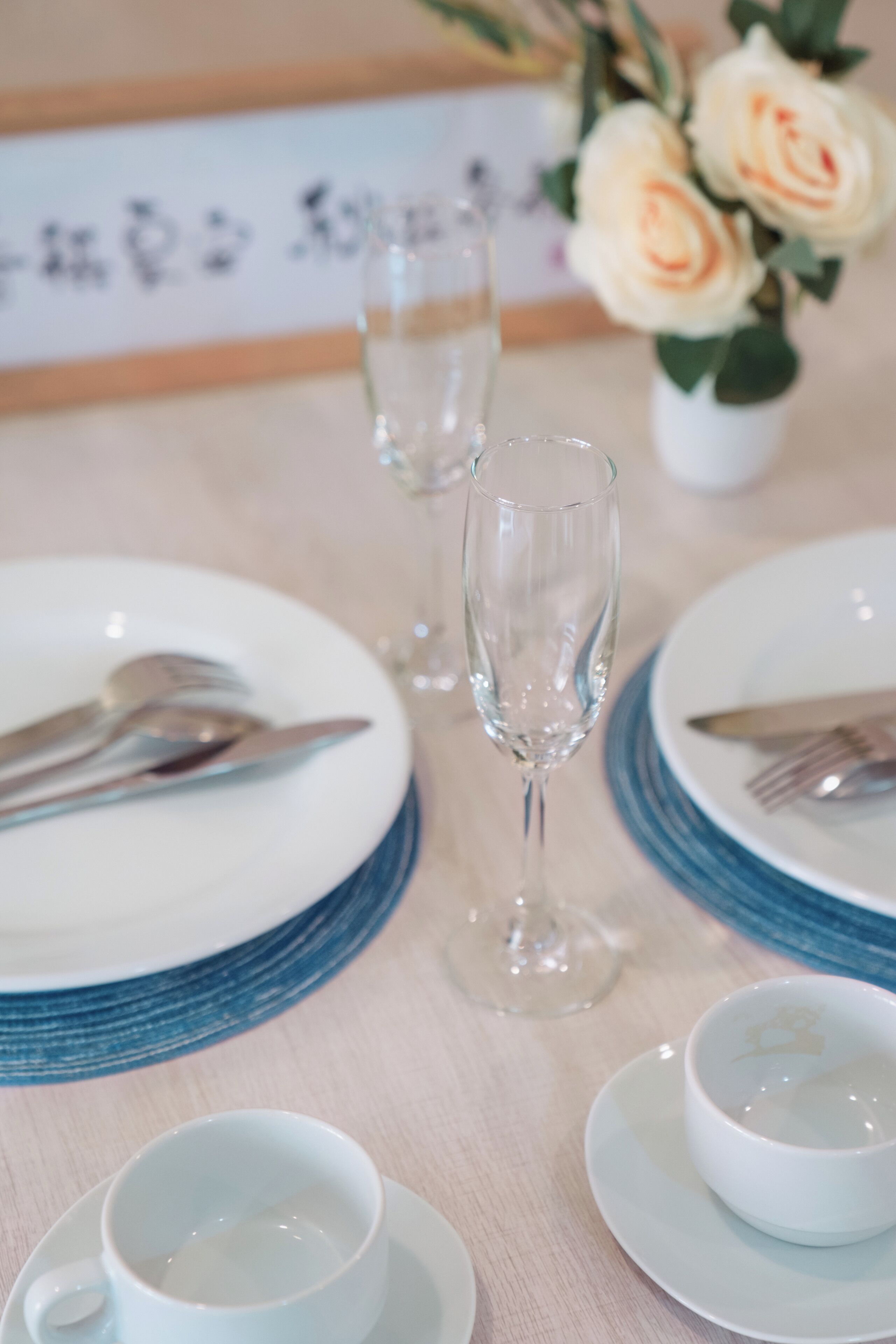 Un tavolo da pranzo apparecchiato con piatti, posate, bicchieri e un vaso con fiori.