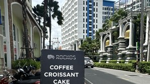 A signboard for Rockos Coffee Croissant Cake with a coffee cup illustration. - Seven Seas Condo Resort steps to  Beach (Pattaya)