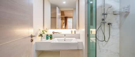 Un baño moderno con ducha de vidrio, un lavamanos blanco y un espejo encima.