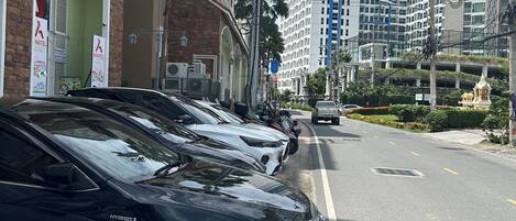 Una fila de coches aparcados a lo largo de una calle urbana, con edificios de varios pisos al fondo.
