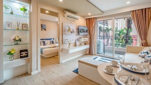 A modern hotel room with a balcony, a seating area, and a dining setup. - Seven Seas Condo Resort steps to  Beach (Pattaya)