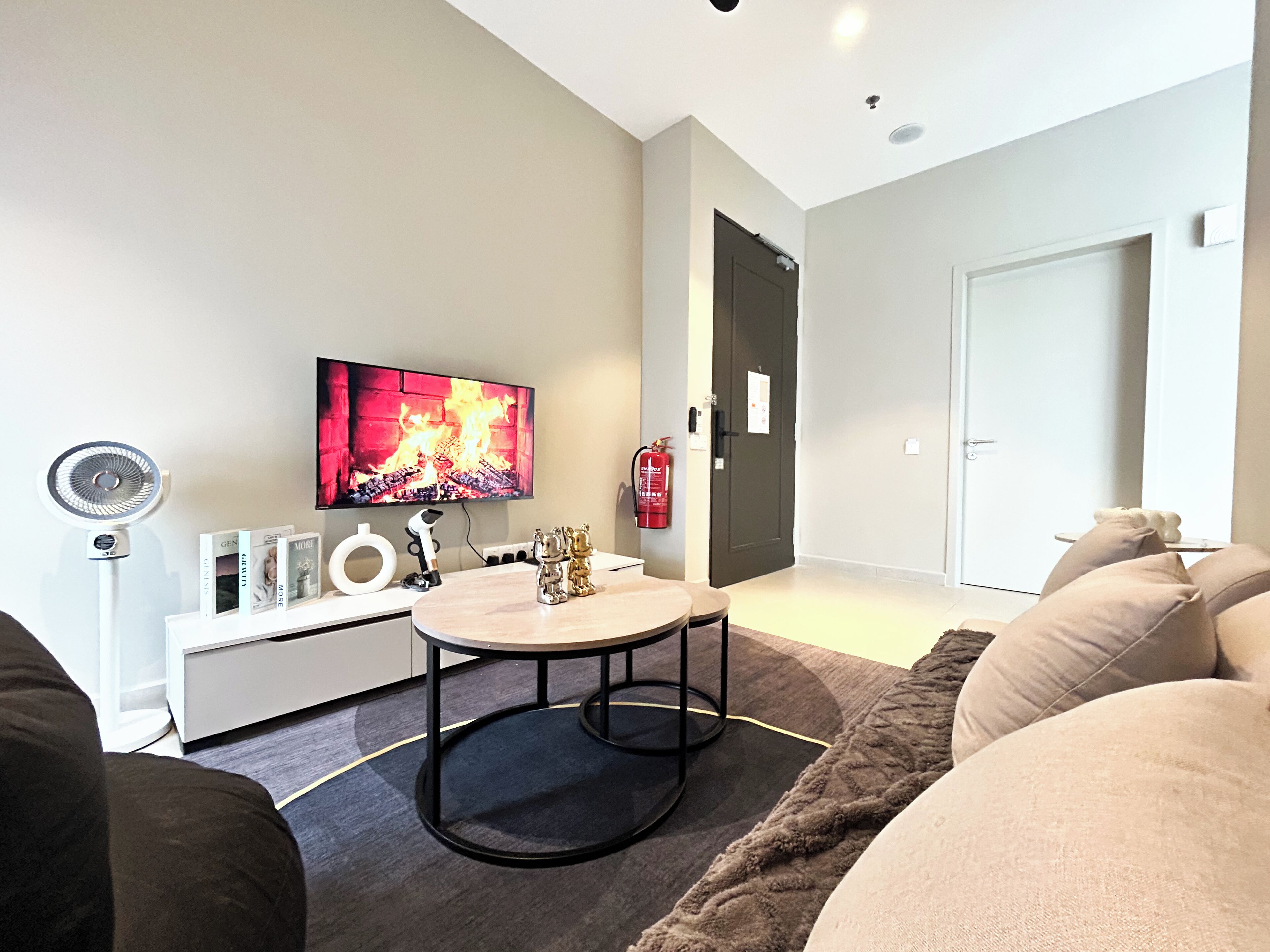 Een moderne woonkamer met een flatscreen televisie, een ronde salontafel, een bank en een open haard.