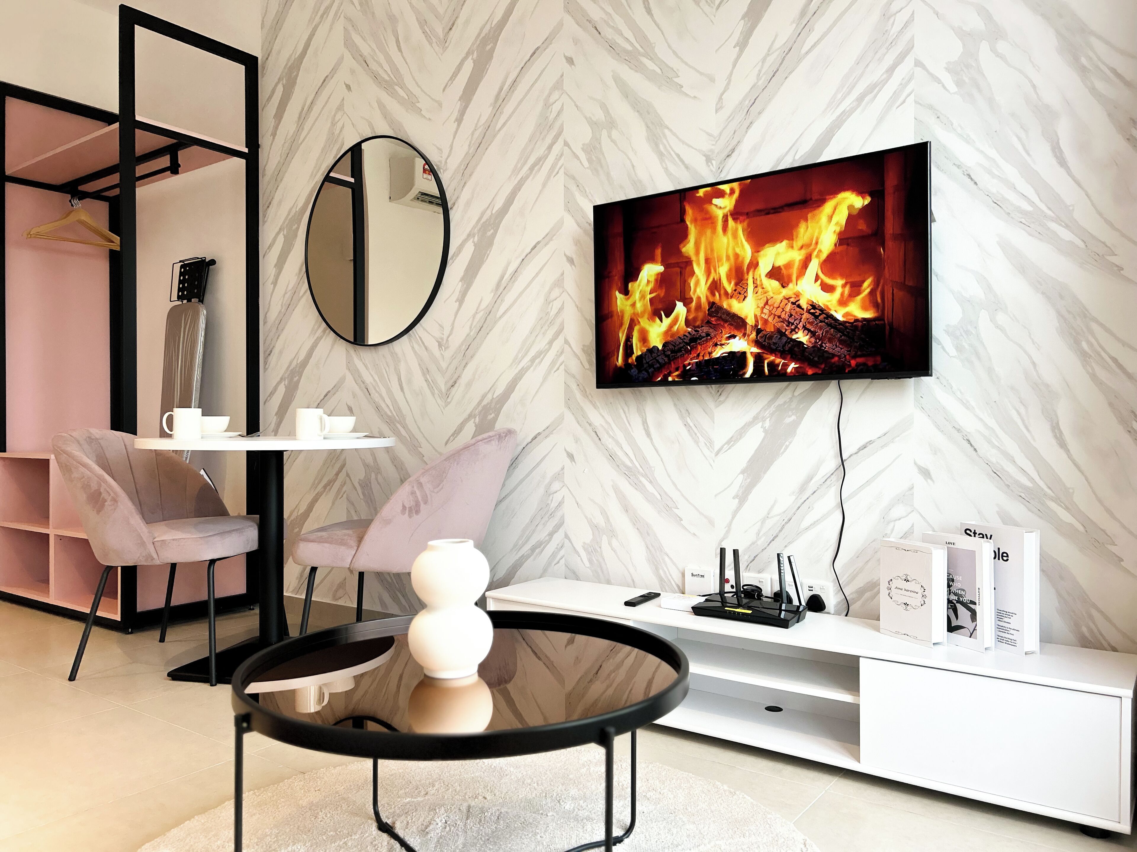 Een moderne woonkamer met een open haard, een televisie en een witte console tafel.
