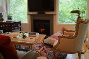 Ein gemütliches Wohnzimmer mit Kamin, Fernseher und bequemen Sessel.