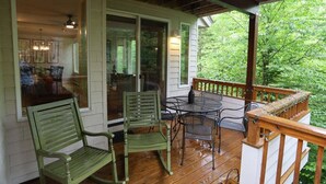 A covered porch with a table and chairs, a bench, and a view of greenery. - Forest Knoll M4, Waterville Valley (Waterville Valley)