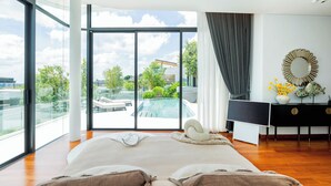 Une chambre spacieuse avec un grand lit, une vue sur une piscine et une salle de bain moderne équipée d’un miroir et d’objets décoratifs.