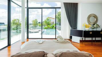 A spacious bedroom with a large bed, a view of a swimming pool, and a modern bathroom with a mirror and decorative items.