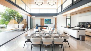 Une salle à manger spacieuse avec une longue table dressée pour six personnes, entourée de chaises modernes.