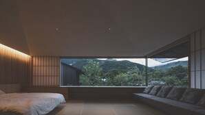 A bedroom with a large window, a bed, and a seating area.