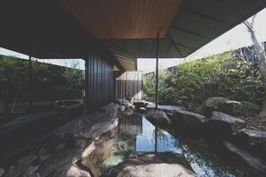 A modern building with a wooden ceiling and a view of a natural landscape with rocks and greenery. - COMICO ART HOUSE YUFUIN (Yufu)