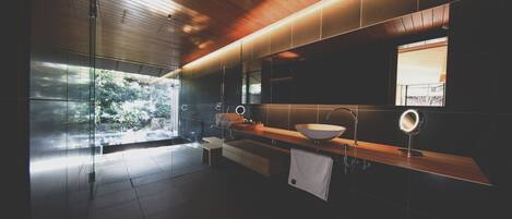 Un baño moderno con un espejo grande, un lavamanos y un banco.