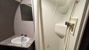 A compact bathroom with a sink, mirror, and shower. - Delightful mobile home with AC in Muskegon (Muskegon)