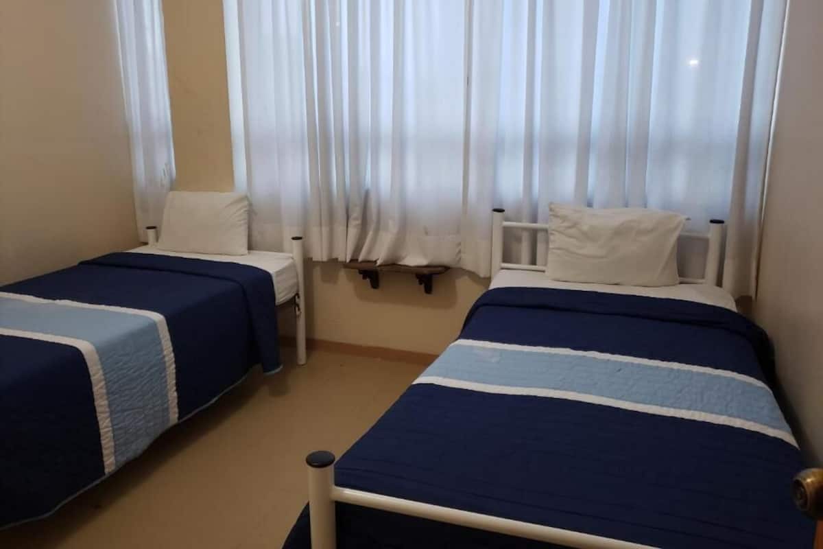 Private room with two single beds and shared bathroom