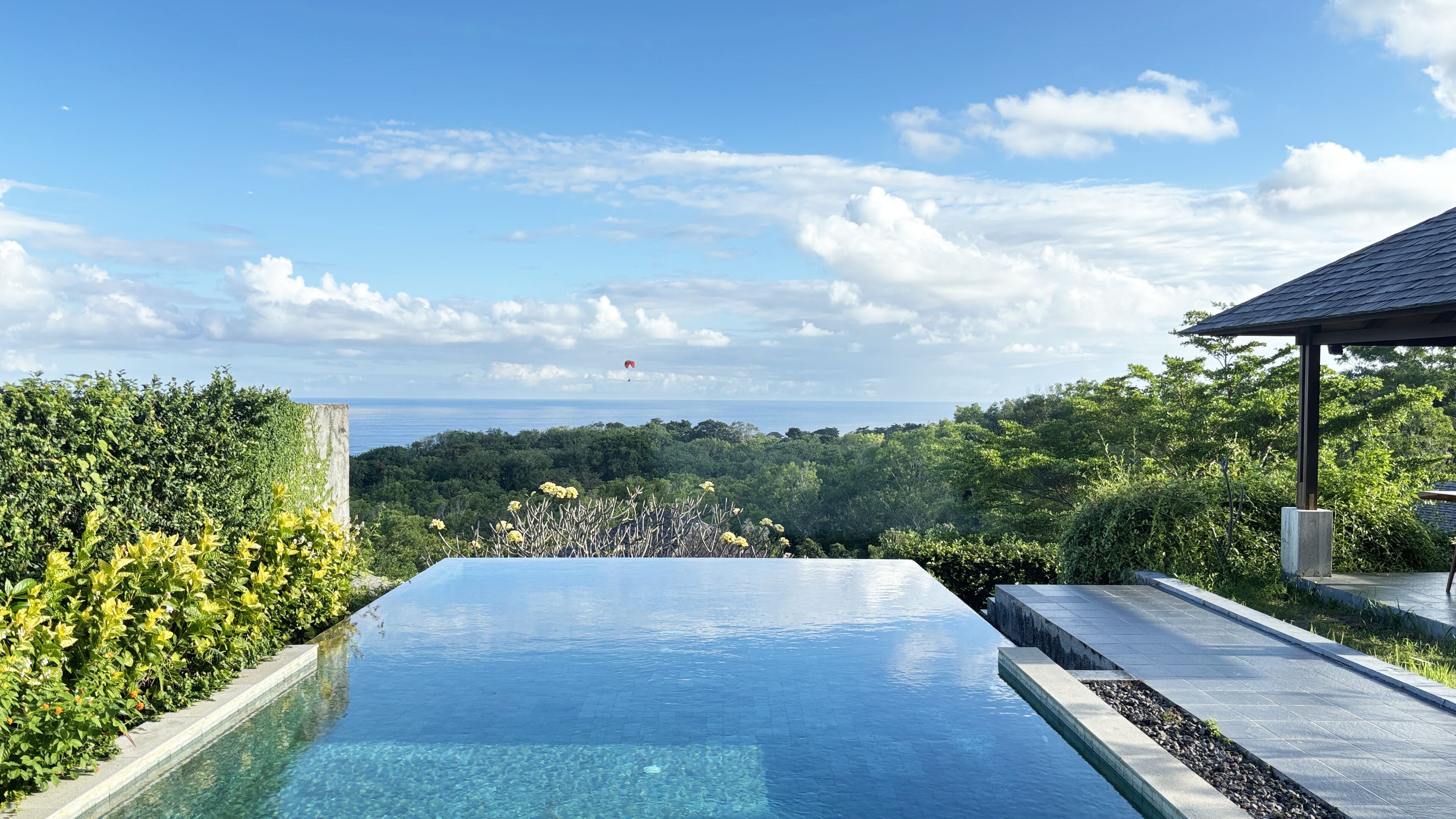 An infinity pool with a clear view of the ocean and a lush green landscape.