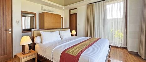 A hotel room with a wooden bed, bedside lamps, a wooden nightstand, a mirror, and a window with curtains.