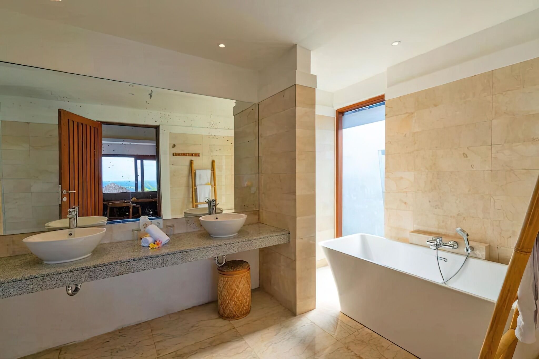 A modern bathroom with two sinks, a large mirror, and a freestanding bathtub.