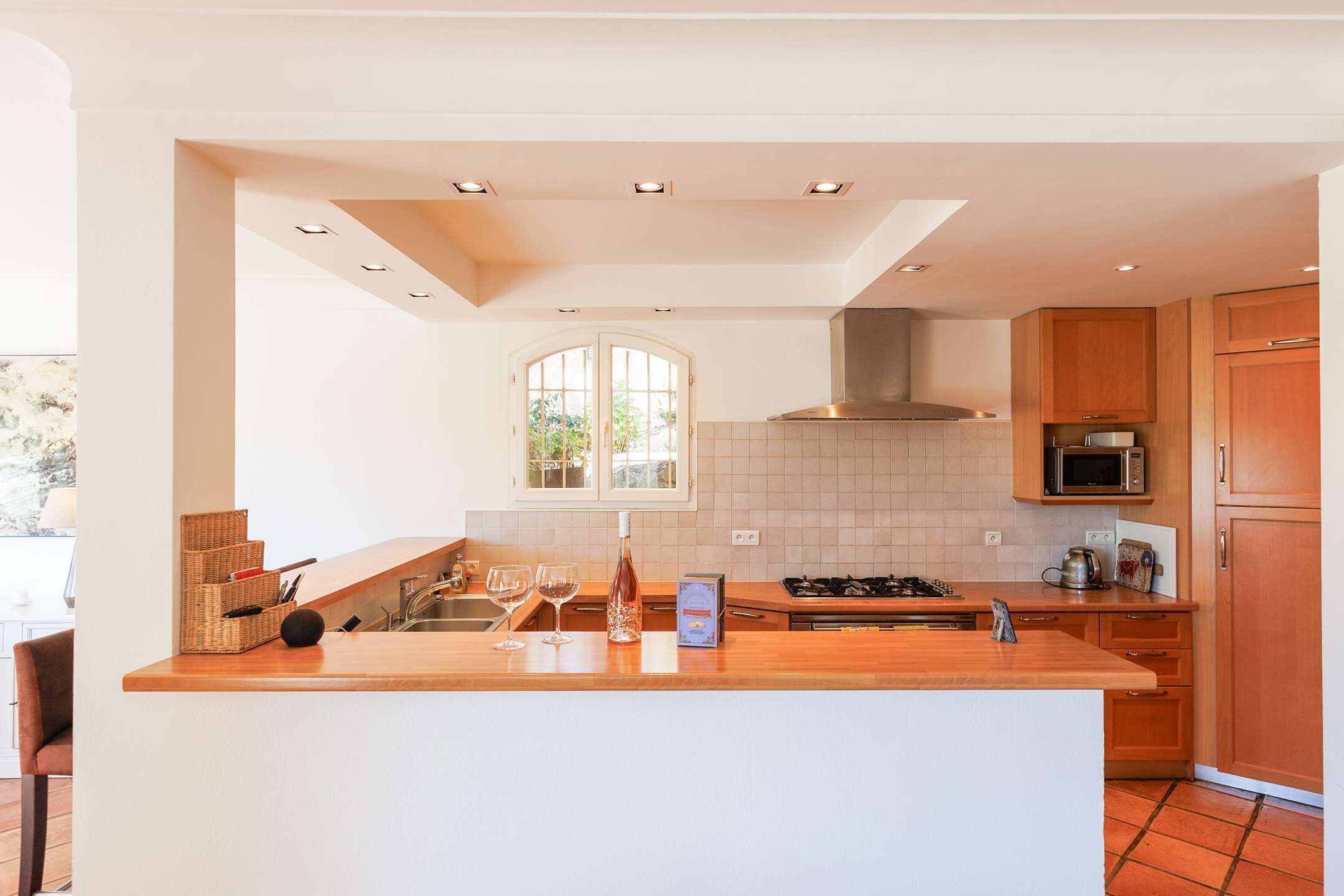 Une cuisine moderne dotée d’un îlot central, de meubles blancs, d’un four à micro-ondes et d’une cuisinière.