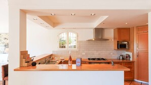 A modern kitchen with a central island, white cabinetry, a microwave, and a stove.