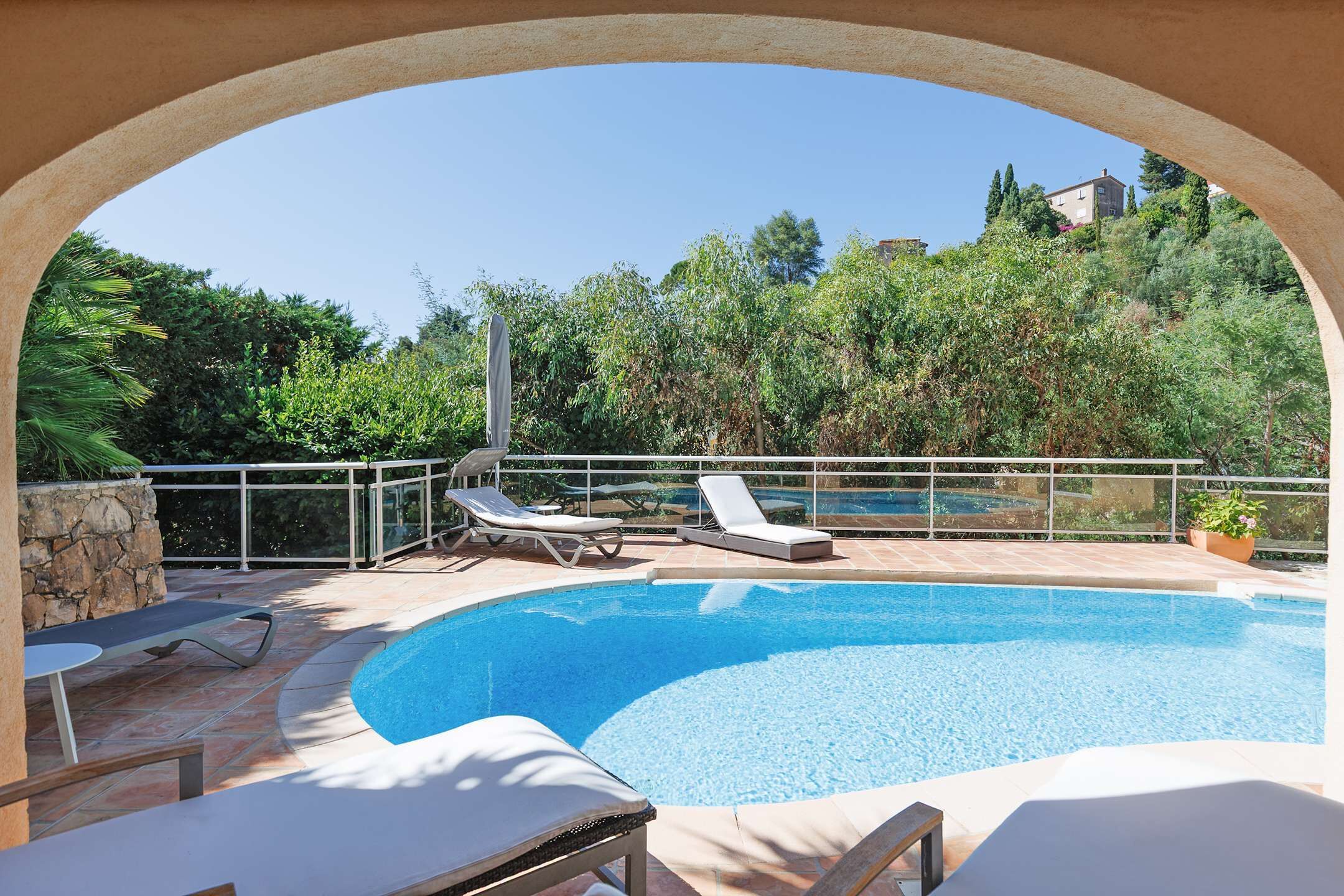 Une piscine extérieure avec des chaises longues et un mur en pierre.