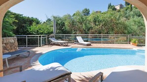 An outdoor swimming pool with lounge chairs and a stone wall.