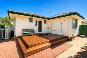 A single-story house with a porch, a bench, and a small door.