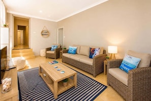 A living room with a sofa, two armchairs, a coffee table, and a lamp.