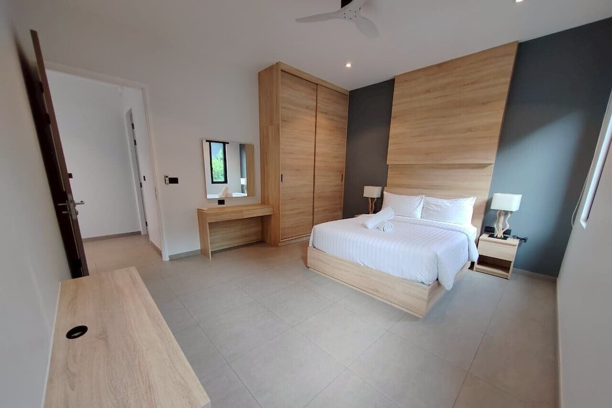 Un dormitorio moderno con cama, mesitas de noche, armario y escritorio.