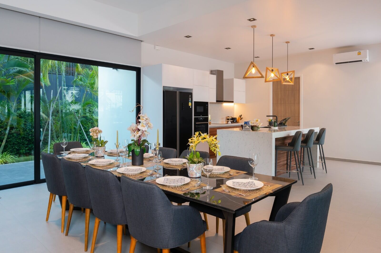 A modern dining area with a large table set for six, surrounded by chairs with wooden legs.