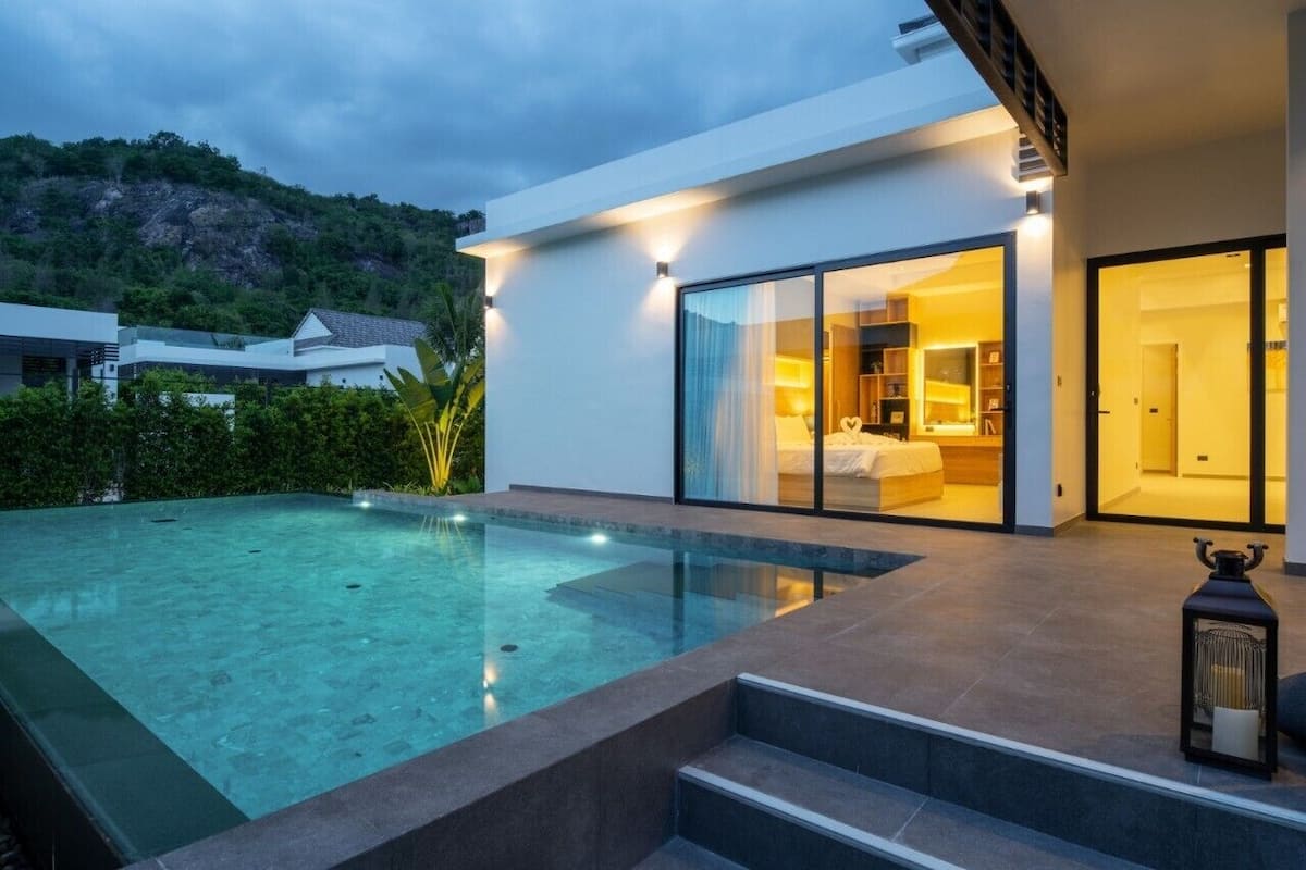 Una casa moderna con piscina, un dormitorio con ventana grande y una escalera que conduce al dormitorio.