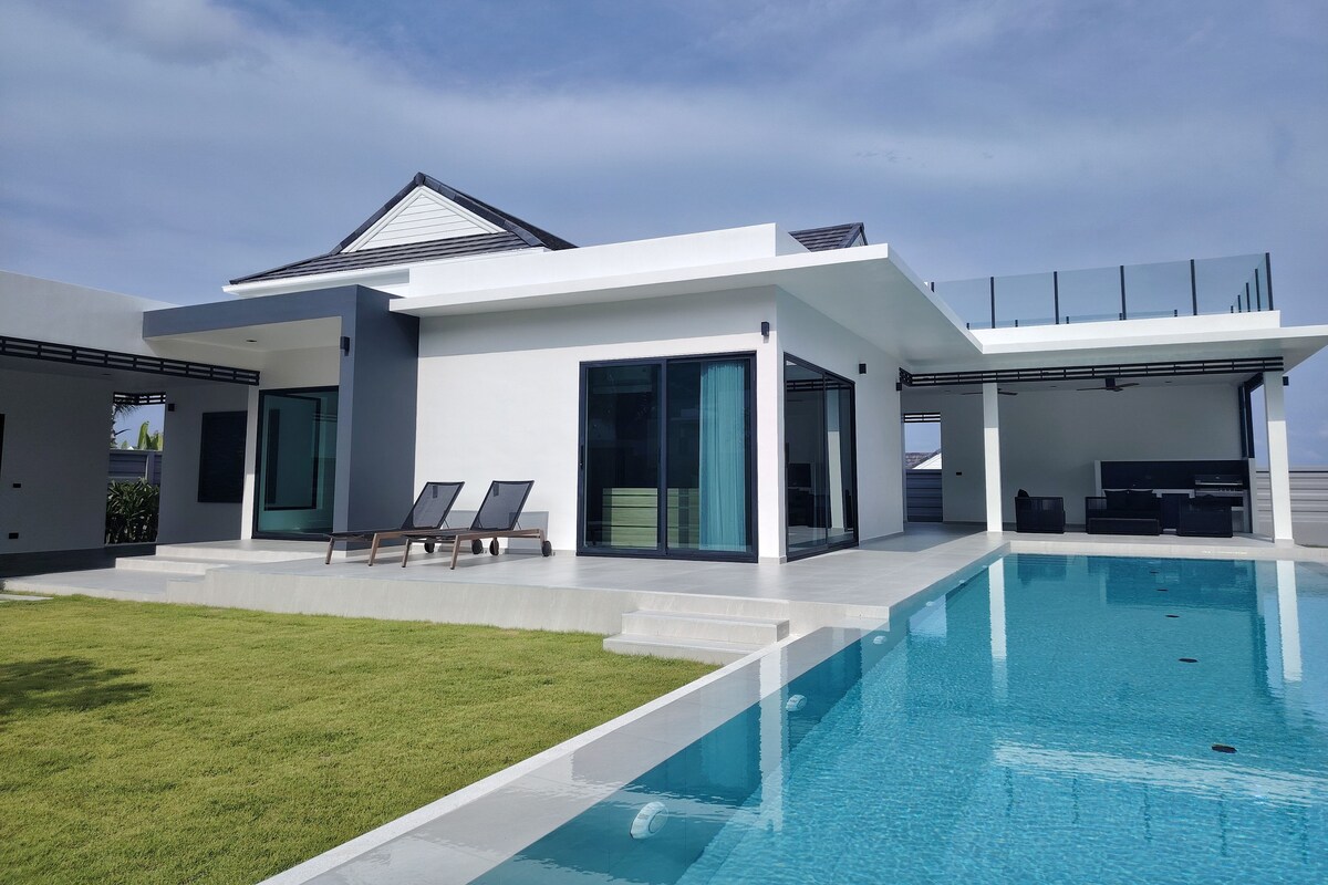 A modern house with a swimming pool, large windows, and a flat roof.
