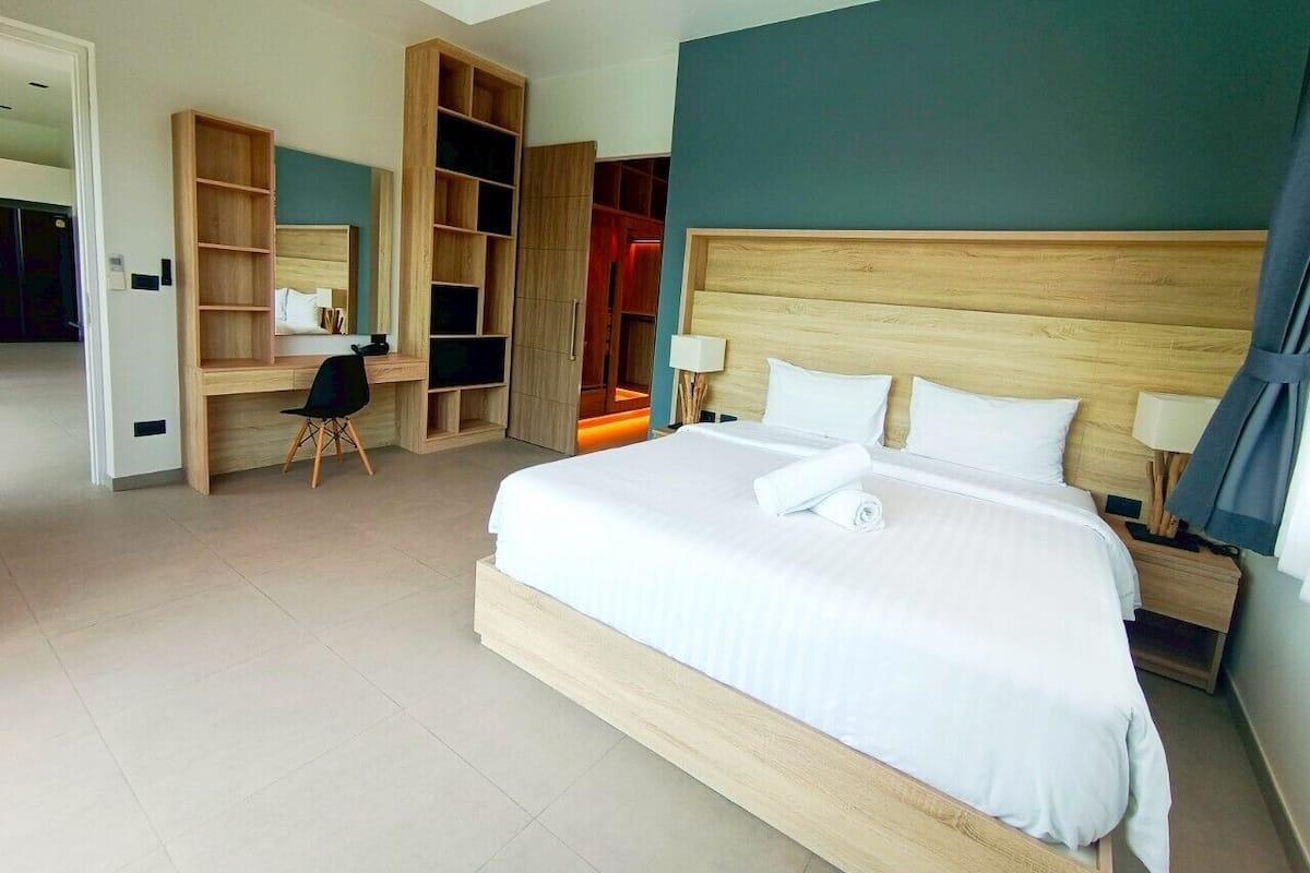 Una habitación de hotel moderna con una cama grande, un escritorio con silla y estantes integrados.