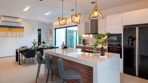Una cocina moderna con una isla central, iluminación colgante y vistas al exterior.