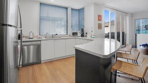 Una cocina moderna con electrodomésticos de acero inoxidable, una isla central y un comedor con sillas de mimbre.