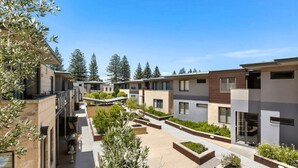 Un moderno complejo residencial con varias edificaciones de dos pisos, terrazas exteriores y cielo despejado.